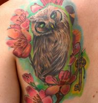 Owl among cherry blossom tattoo